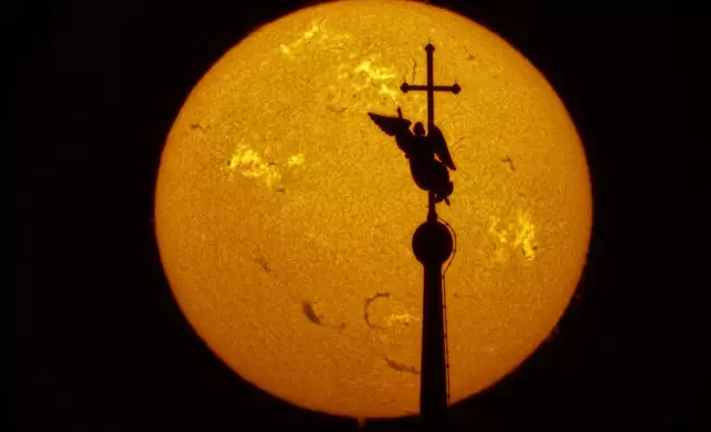 In this photo taken with a solar telescope, the city landmark, a weather vane in the form of an angel fixed atop a spire of the Saints Peter and Paul Cathedral, is silhouetted against the sun that shows solar activity zones, at sunset in St. Petersburg, Russia, Monday, March 30, 2026. (AP Photo/Dmitri Lovetsky)