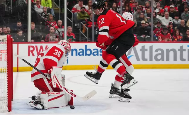 Detroit Red Wings goaltender John Gibson (36) stops a shot while protecting the net from New Jersey Devils' Cody Glass (12) during the second period of an NHL hockey game Sunday, March 8, 2026, in Newark, N.J. (AP Photo/Frank Franklin II)