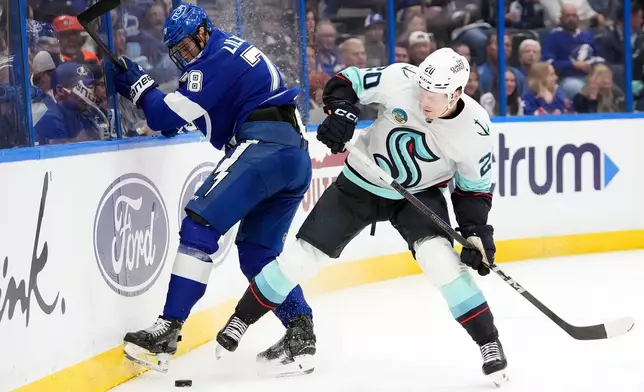 Tampa Bay Lightning defenseman Emil Lilleberg (78) beats Seattle Kraken right wing Eeli Tolvanen (20) to the puck during the third period of an NHL hockey game Thursday, March 26, 2026, in Tampa, Fla. (AP Photo/Chris O'Meara)