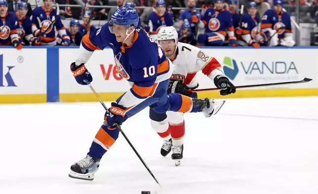 New York Islanders center Brayden Schenn (10) shoots and scores a goal in front of Florida Panthers defenseman Dmitry Kulikov in the second period of an NHL hockey game Saturday, March 28, 2026, in Elmont, N.Y. (AP Photo/Adam Hunger)