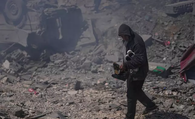 A man carries shoes from his destroyed house that was hit by Israeli airstrikes hit several houses in Sir al-Gharbiyeh village south Lebanon, Sunday, March, 8, 2026. (AP Photo/Mohammed Zaatari)