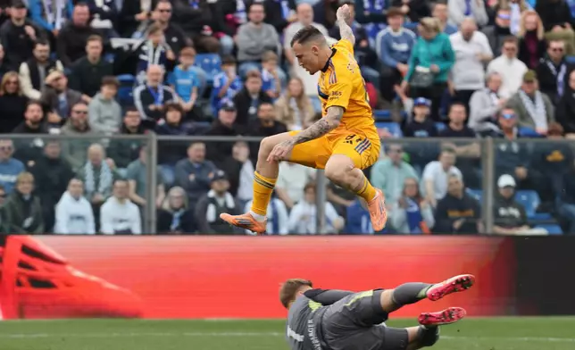 Pisa's Malthe Hojholt jumps over Como goalkeeper Jean Butez during the Serie A soccer match between Como and Pisa in Como, Italy, Sunday March 22, 2026. (Antonio Saia/LaPresse via AP)