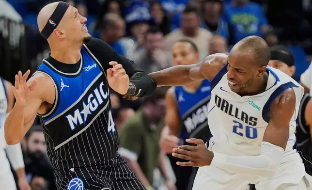 Dallas Mavericks forward Khris Middleton (20) is called for a loose ball foul as he grabs on to Orlando Magic guard Jalen Suggs (4) during the second half of an NBA basketball game, Thursday, March 5, 2026, in Orlando, Fla. (AP Photo/John Raoux)
