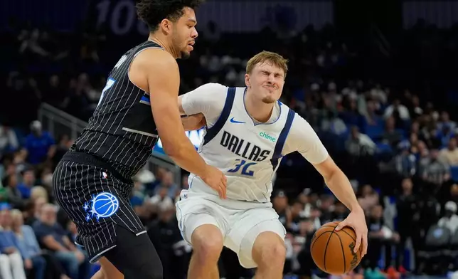 Dallas Mavericks forward Cooper Flagg (32) grimaces as he collides with Orlando Magic forward Noah Penda, left, during the first half of an NBA basketball game, Thursday, March 5, 2026, in Orlando, Fla. (AP Photo/John Raoux)