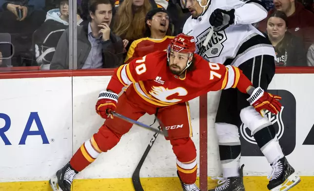 Los Angeles Kings' Cody Ceci, right, is checked by Calgary Flames' Ryan Lomberg during the second period of an NHL hockey game in Calgary on Tuesday, March 24, 2026. (Jeff McIntosh/The Canadian Press via AP)