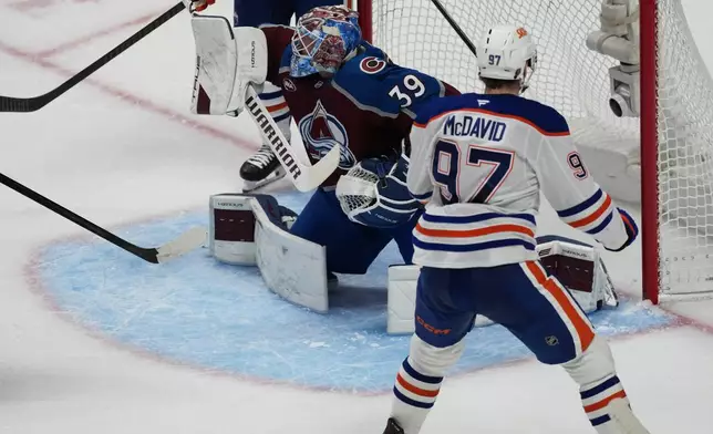 Edmonton Oilers center Connor McDavid, front, scores a power-play goal against Colorado Avalanche goaltender MacKenzie Blackwood in the third period of an NHL hockey game Tuesday, March 10, 2026, in Denver. (AP Photo/David Zalubowski)