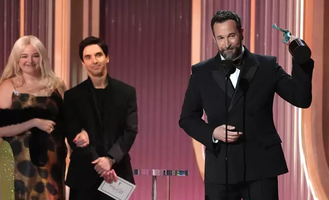 Noah Wyle, right, accepts the award for outstanding performance by a male actor in a drama series for "The Pitt" during the 32nd Annual Actor Awards on Sunday, March 1, 2026, at the Shrine Auditorium and Expo Hall in Los Angeles. Megan Stalter, far left, and Paul W. Downs loook on from left.(AP Photo/Chris Pizzello)