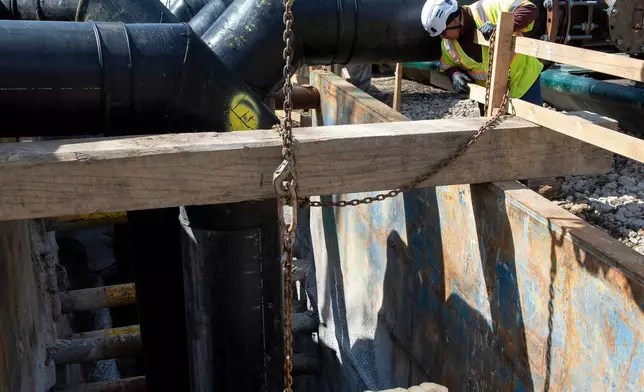 A worker keeps watch as a gate is raised to allow raw sewage to flow to an interceptor pipe along the C&amp;O Canal, beside the Potomac River, in Cabin John, Md., Saturday, March 14, 2026. (AP Photo/Cliff Owen)