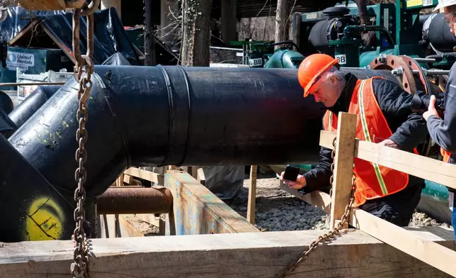 Noel Boxer, an external affairs officer with FEMA, inspects the flow of raw sewage, after a gate was raised to resume the flow, along the Potomac River, in Cabin John, Md., Saturday, March 14, 2026. (AP Photo/Cliff Owen)