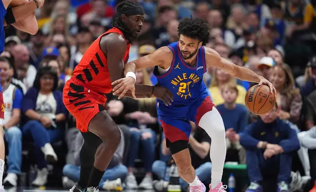 Denver Nuggets guard Jamal Murray, right, drives past Portland Trail Blazers guard Jrue Holiday, left, in the first half of an NBA basketball game Sunday, March 22, 2026, in Denver. (AP Photo/David Zalubowski)