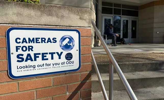 A person sits at the front door of Constant Hall, where yesterday shooting occurred on Friday, March 13, 2026 at Old Dominion Universiy in Norfolk, Va. (AP Photo/Allen G. Breed).