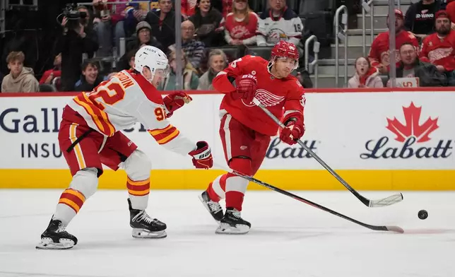 Detroit Red Wings right wing Patrick Kane (88) shoots on Calgary Flames defenseman Matvei Gridin (94) in the first period of an NHL hockey game Monday, March 16, 2026, in Detroit. (AP Photo/Paul Sancya)