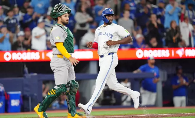 Toronto Blue Jays' Jesús Sánchez (12) scores a run in the seventh inning of a baseball game against the Athletics in Toronto, Saturday, March 28, 2026. (Frank Gunn/The Canadian Press via AP)