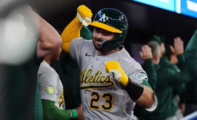 Athletics' Shea Langeliers (23) celebrates in the dugout with teammates after he hit a grand slam in the seventh inning of a baseball game against the Toronto Blue Jays in Toronto, Saturday, March 28, 2026. (Frank Gunn/The Canadian Press via AP)