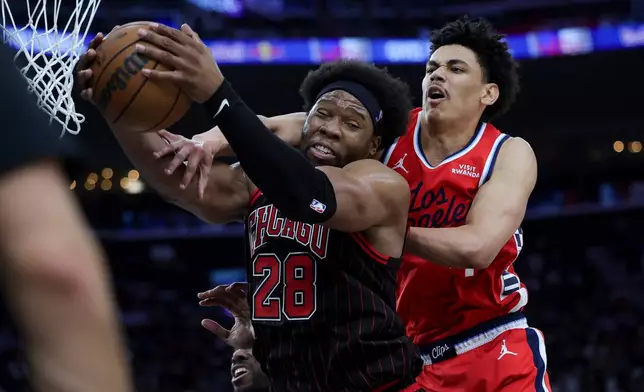Chicago Bulls forward Guerschon Yabusele, left, and Los Angeles Clippers guard Kobe Sanders, right, vie for a rebound during the first half of an NBA basketball game Friday, March 13, 2026, in Inglewood, Calif. (AP Photo/Ryan Sun)
