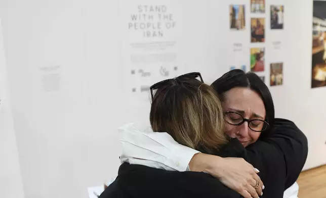 Forough Jafari hugs a visitor at a dedicated memorial space for the lives lost in Iran during a gathering in New York, on Saturday, March 14, 2026, for the upcoming Nowruz, Iranian/Persian New Year's day. (AP Photo/Heather Khalifa)