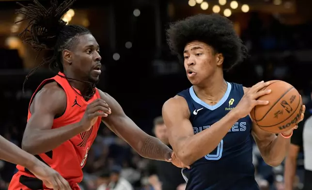 Memphis Grizzlies forward Jaylen Wells, right, handles the ball against Portland Trail Blazers guard Jrue Holiday in the first half of an NBA basketball game, Wednesday, March 4, 2026, in Memphis, Tenn. (AP Photo/Brandon Dill)