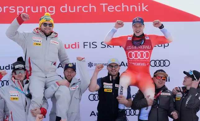 Switzerland's Marco Odermatt, right, celebrates with the team after taking third place in an alpine ski, men's World Cup downhill race, as Switzerland's Niels Hintermann celebrates after announcing his retirement, in Courchevel, France, Friday, March 13, 2026. (AP Photo/Giovanni Auletta)