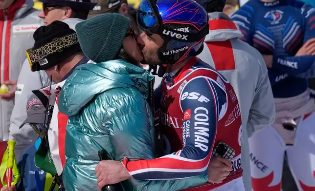 France's Adrien Theaux kisses his partner at the finish area of an alpine ski, men's World Cup downhill, after competing in his last race, in Courchevel, France, Friday, March 13, 2026. (AP Photo/Giovanni Auletta)