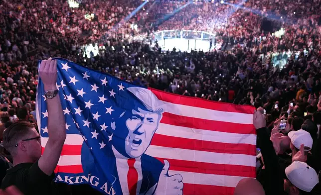 FILE - People hold a flag as President-elect Donald Trump arrives at UFC 309 at Madison Square Garden, Nov. 16, 2024, in New York. (AP Photo/Evan Vucci, File)