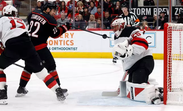 Carolina Hurricanes' Logan Stankoven (22) tries to play the puck in front of New Jersey Devils goaltender Jacob Markstrom (25) during the second period of an NHL hockey game in Raleigh, N.C., Saturday, March 28, 2026. (AP Photo/Karl DeBlaker)