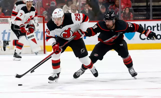 Carolina Hurricanes' William Carrier (28) tries to take the puck from New Jersey Devils' Lenni Hameenaho (29) during the first period of an NHL hockey game in Raleigh, N.C., Saturday, March 28, 2026. (AP Photo/Karl DeBlaker)