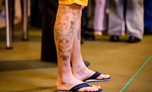 A cat breeder, donning cat-themed tattoos, attends an international feline beauty competition, dubbed the Feline Oscars, featuring more than 200 cats, in Bucharest, Romania, Saturday, March 21, 2026. (AP Photo/Andreea Alexandru)