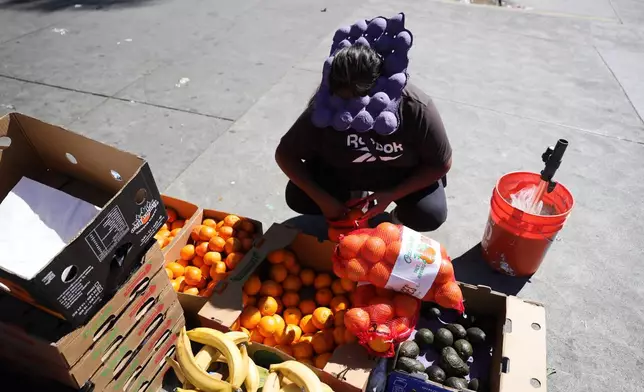 A street vendor uses an egg carton to shield from from during an unseasonably hot day at MacArthur Park on Thursday, March 12, 2026, in Los Angeles. (AP Photo/Ryan Sun)