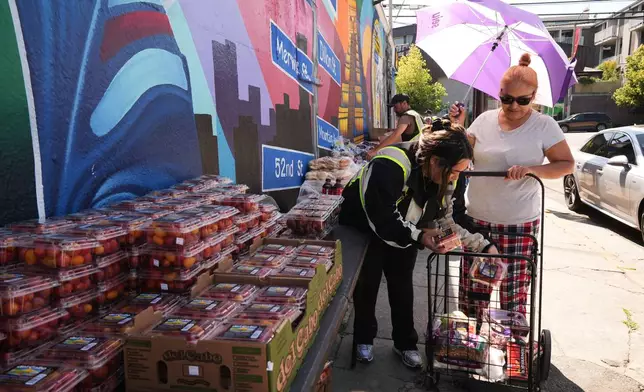 Food is distributed at a donation site during an unseasonably warm day Wednesday, March 11, 2026, in Los Angeles. (AP Photo/Damian Dovarganes)