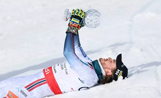 Norway's Atle Lie McGrath lies on the snow, holding the globe trophy for the alpine ski, men's slalom discipline, at the Lillehammer World Cup Finals, in Hafjell, Norway, Wednesday, March 25, 2026. (AP Photo/Marco Trovati)