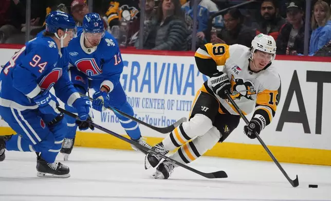 Pittsburgh Penguins center Connor Dewar, right, collects the puck as Colorado Avalanche left wing Joel Kiviranta (94) and right wing Valeri Nichushkin, back left, defend in the second period of an NHL hockey game Monday, March 16, 2026, in Denver. (AP Photo/David Zalubowski)