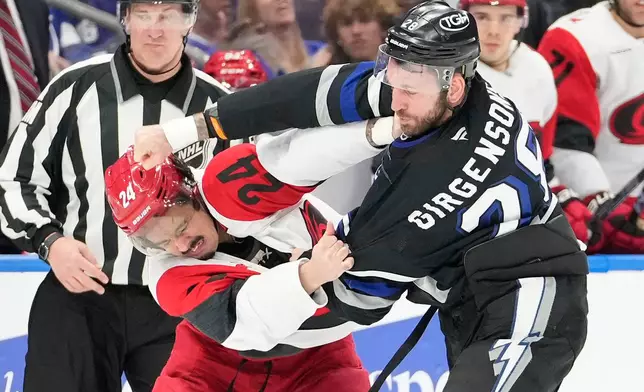 Tampa Bay Lightning center Zemgus Girgensons (28) and Carolina Hurricanes center Seth Jarvis (24) fight during the first period of an NHL hockey game Saturday, March 14, 2026, in Tampa, Fla. (AP Photo/Chris O'Meara)