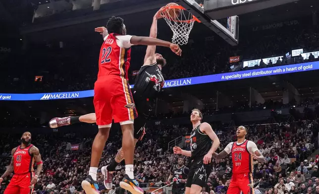 Toronto Raptors' Sandro Mamukelashvili, center right, dunks against New Orleans Pelicans' Derik Queen (22) during first-half NBA basketball game action in Toronto, Friday March 27 2026. (Chris Young/The Canadian Press via AP)