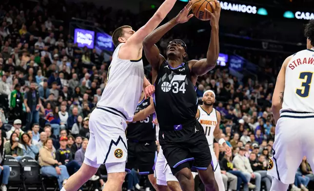 Utah Jazz center Oscar Tshiebwe (34) drives to the basket while guarded by Denver Nuggets center Nikola Jokic, left, during the first half of an NBA basketball game, Monday, March 2, 2026, in Salt Lake City. (AP Photo/Tyler Tate)