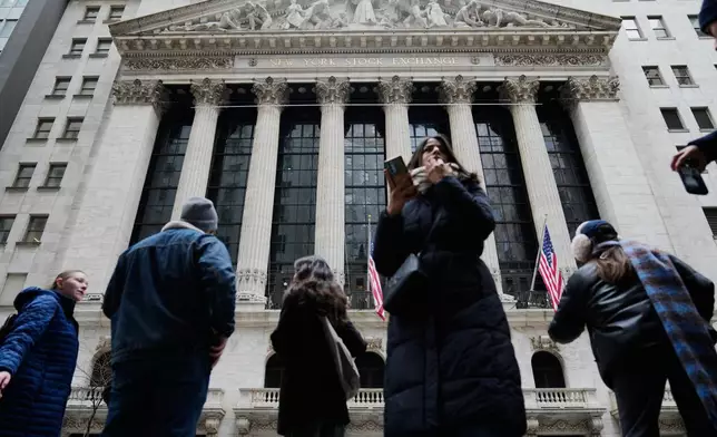 Pedestrians mill about outside the New York Stock Exchange in New York, Friday, March 6, 2026. (AP Photo/Seth Wenig)