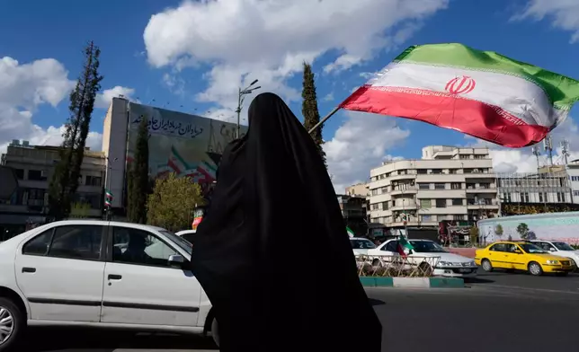 A woman waves an Iranian flag during a campaign in support of the government at the Enqelab-e-Eslami, or Islamic Revolution, square in downtown Tehran, Iran, Monday, March 30, 2026. (AP Photo/Vahid Salemi)