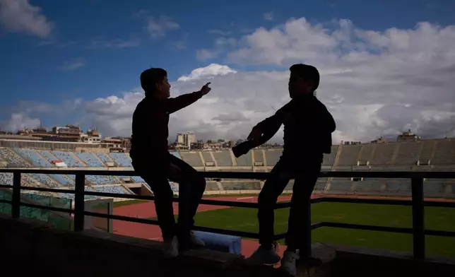 Displaced children talk inside Camille Chamoun Sports City Stadium, now used as a shelter for people displaced by Israeli airstrikes in southern Lebanon, in Beirut, Lebanon, Monday, March 30, 2026. (AP Photo/Emilio Morenatti)