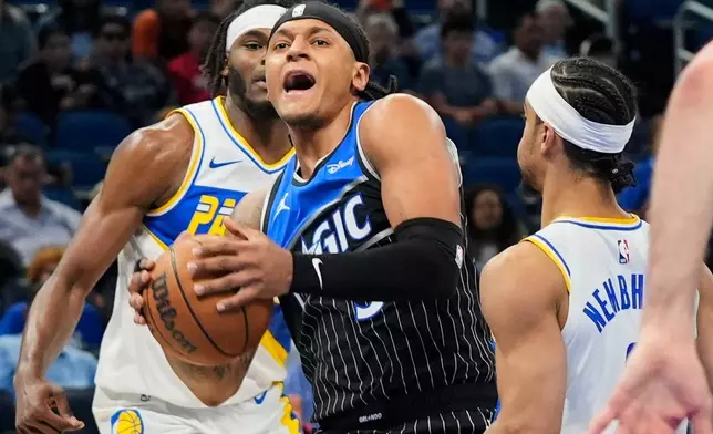 Orlando Magic forward Paolo Banchero, center, tries to move past Indiana Pacers forward Jarace Walker, back left, and guard Andrew Nembhard, right, during the first half of an NBA basketball game, Monday, March 23, 2026, in Orlando, Fla. (AP Photo/John Raoux)