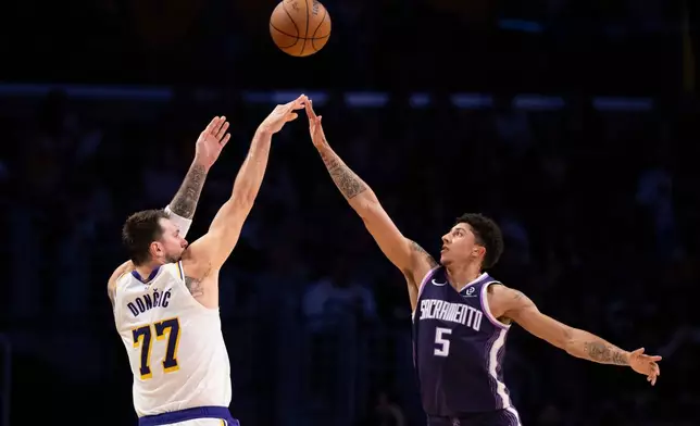 Los Angeles Lakers guard Luka Doncic, left, shoots as Sacramento Kings guard Nique Clifford defends during the first half of an NBA basketball game in Los Angeles, Sunday, March 1, 2026. (AP Photo/Kyusung Gong)