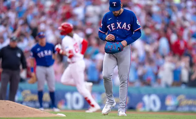 Texas Rangers stating pitcher Nathan Eovaldi, right, reacts to giving up a three-run home run to Philadelphia Phillies' Alec Bohm, left, during the fifth inning of an opening-day baseball game, Thursday, March 26, 2026, in Philadelphia. (AP Photo/Chris Szagola)