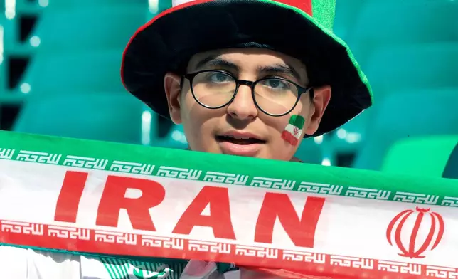 FILE - An Iranian fan holds his national team banner prior to the Asian Cup quarterfinal soccer match between Japan and Iran at Education City Stadium in Al Rayyan, Qatar, Feb. 3, 2024. (AP Photo/Hussein Sayed, file)