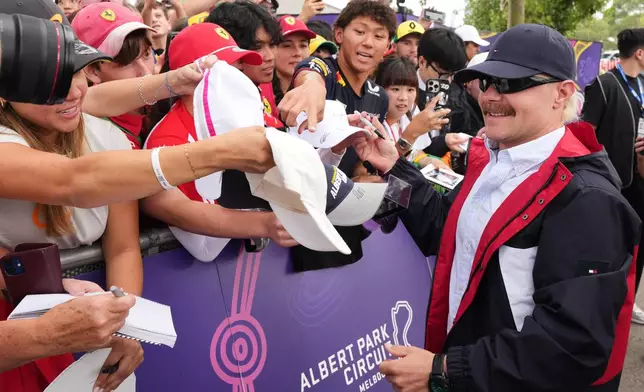 Cadillac driver Valtteri Bottas of Finland signs autographs as he arrives ahead of the first practice session for the Australian Formula One Grand Prix at Albert Park, in Melbourne, Australia, Friday, March 6, 2026. (AP Photo/Scott Barbour)