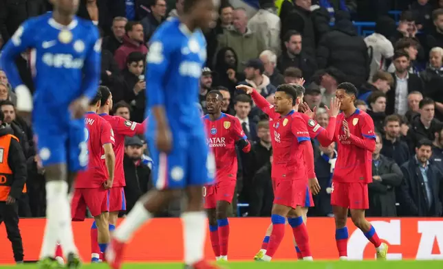 Paris Saint-Germain players celebrate after PSG's Senny Mayulu scored his side's third goal during the Champions League soccer match between Chelsea and Paris Saint-Germain in London, England, Tuesday, March 17, 2026. (AP Photo/Kin Cheung)