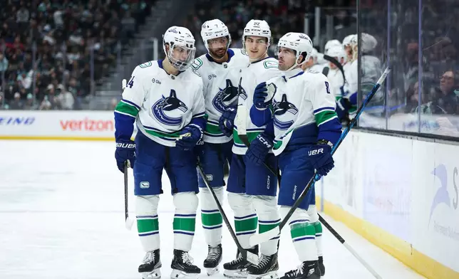 Vancouver Canucks defenseman Zeev Buium (24), defenseman Pierre-Olivier Joseph (7), left wing Liam Ohgren (92) and right wing Conor Garland (8), left to right, celebrate a goal scored by left wing Liam Ohgren (92) in the second period against the Seattle Kraken during an NHL hockey game Saturday, Feb. 28, 2026, in Seattle. (AP Photo/Kevin Ng)