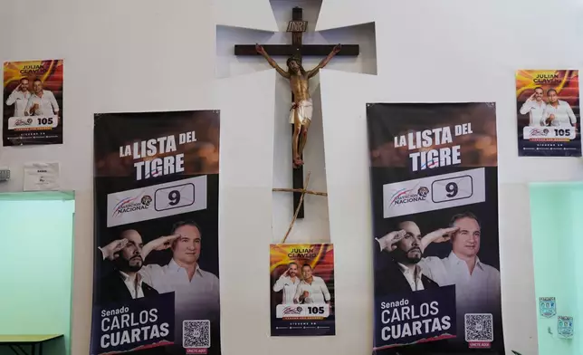 Electoral posters promoting presidential candidate Abelardo de la Espriella and legislative candidates hang on a wall next to a crucifix of Jesus Christ at the Corabastos, the largest food distribution center in Bogota, Colombia, Saturday, Feb. 28, 2026. (AP Photo/Fernando Vergara)