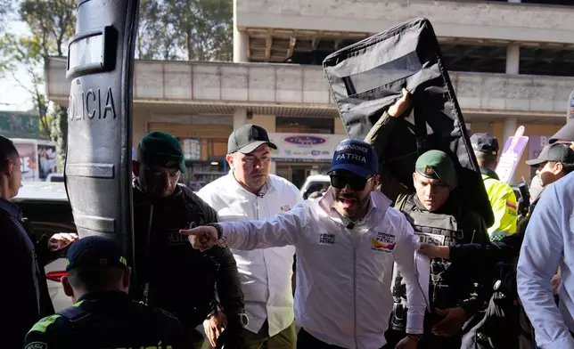 Police hold up shields protecting presidential candidate Abelardo de la Espriella as he points while speaking during a campaign rally at the Corabastos, the largest food distribution center, in Bogota, Colombia, Saturday, Feb. 28, 2026. (AP Photo/Fernando Vergara)