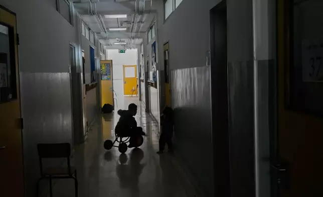 A displaced boy who fled Israeli strikes in southern Lebanon with his family plays on a bicycle in a classroom corridor at a school turned into a shelter in Beirut, Lebanon, Tuesday, March 10, 2026. (AP Photo/Hussein Malla)