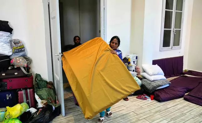 A displaced migrant woman who among many others fled Israeli strikes in southern and eastern Lebanon and Beirut's southern suburbs carries mattresses at Saint Joseph Church, which has been turned into a shelter for displaced migrants, mostly from African nations, in Beirut, Wednesday, March 11, 2026. (AP Photo/Hussein Malla)