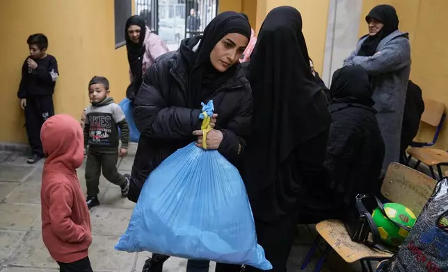 Displaced people fleeing Israeli airstrikes in southern Lebanon and Dahiyeh, Beirut's southern suburbs, arrive at a school turned into a shelter in Beirut, Lebanon, Saturday, March 7, 2026. (AP Photo/Bilal Hussein)