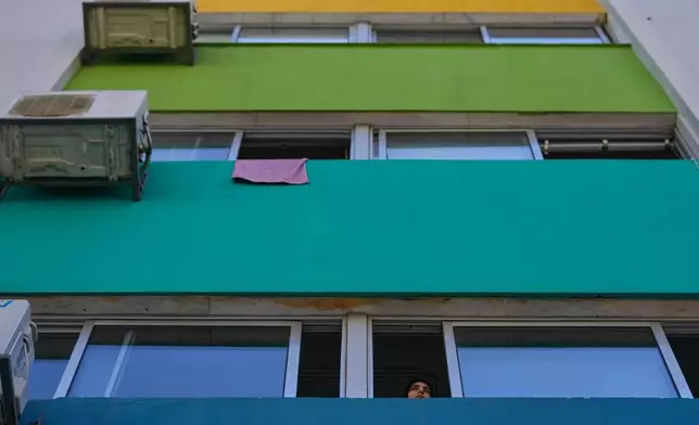 A displaced woman who fled Israeli strikes in southern Lebanon looks through a classroom window at a school turned into a shelter in Beirut, Lebanon, Tuesday, March 10, 2026. (AP Photo/Hussein Malla)
